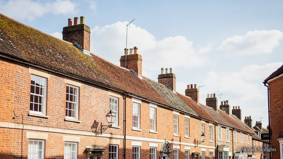Row of red-brick terraced houses with chimneys along a street