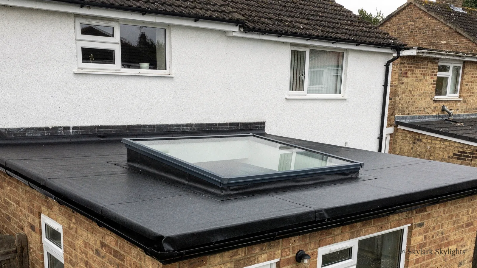 Flat rooflight on an extension roof against a rendered house