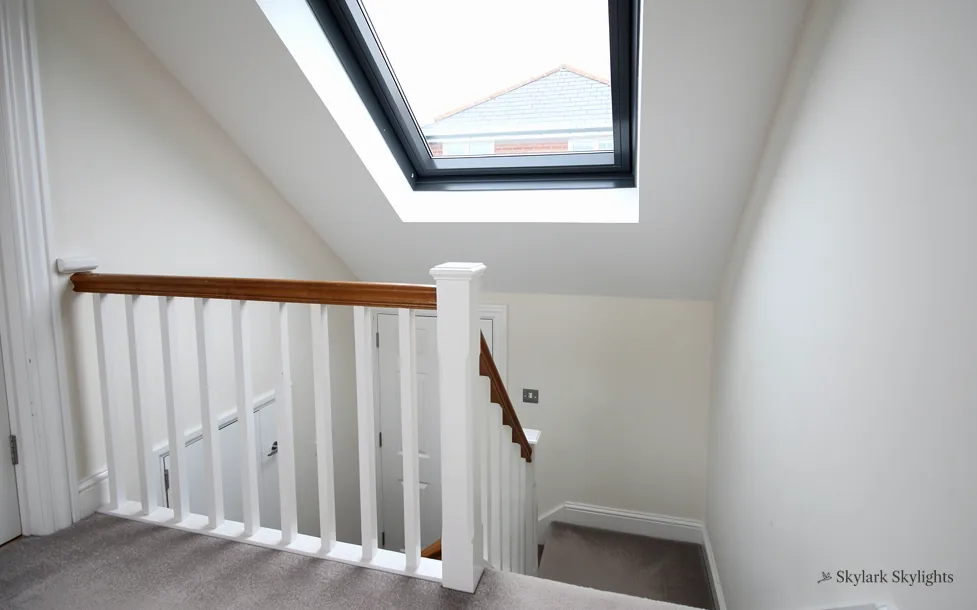 Stairwell with a white banister beneath a roof window