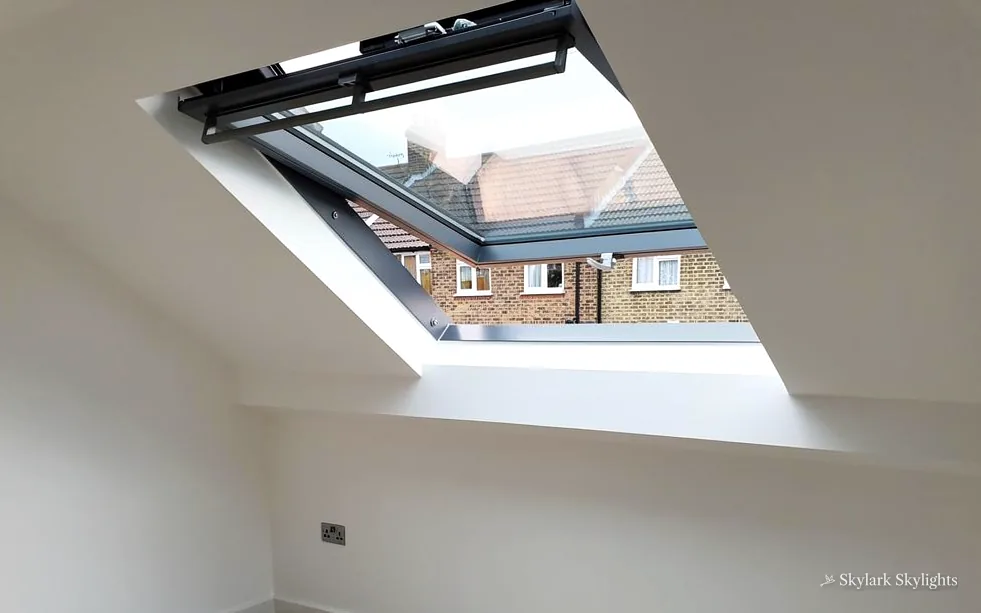 Looking up at a black-framed roof window with houses beyond