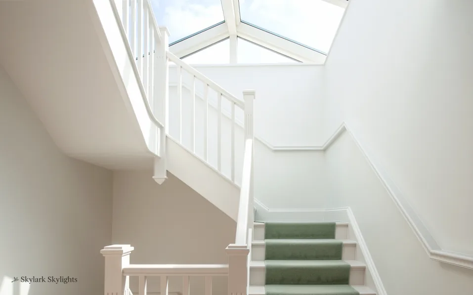 Stairs with a green runner rising towards a roof lantern