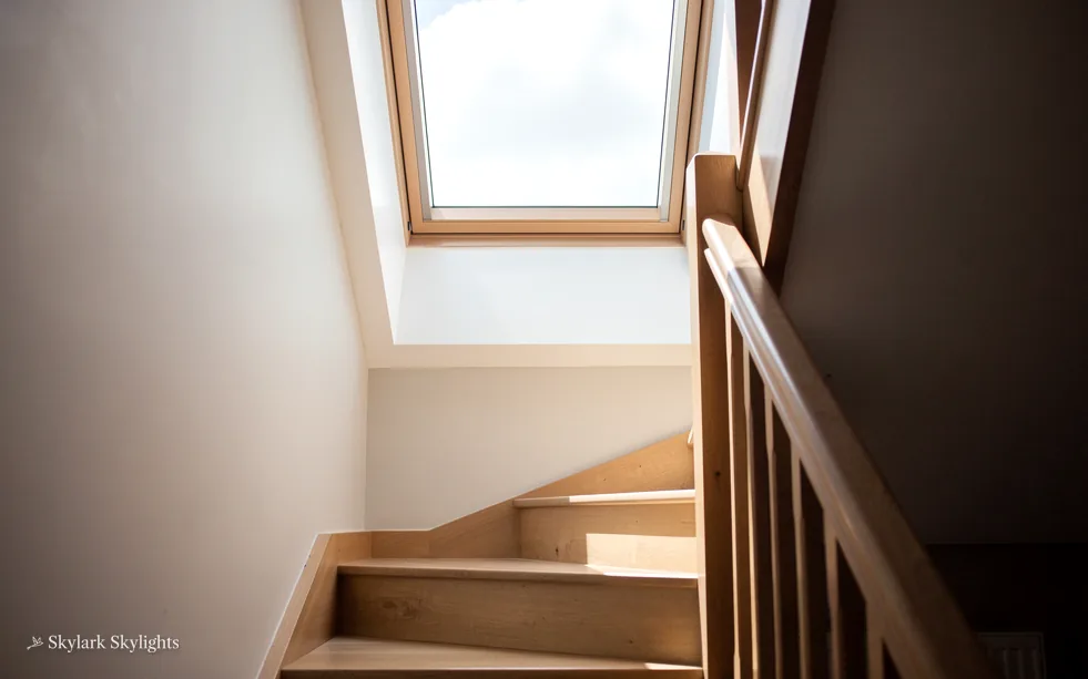 Winding wooden staircase under a roof window