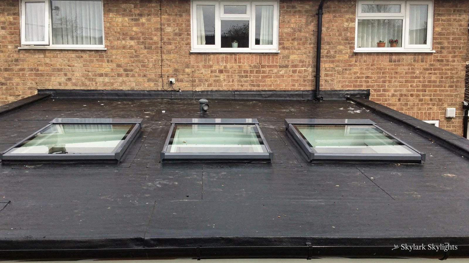 Three flat rooflights on the roof of a brick extension