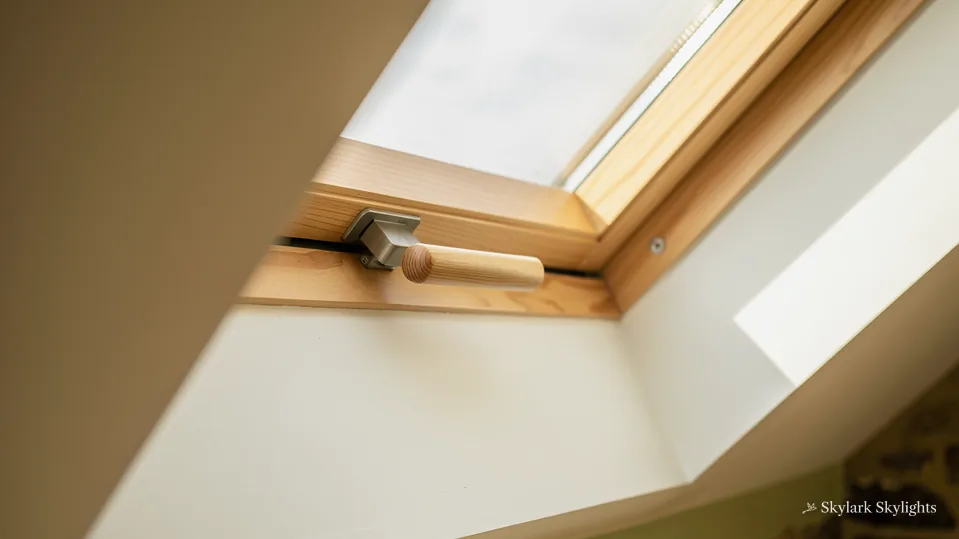 Deep wooden lining of a roof window throwing daylight onto a white wall