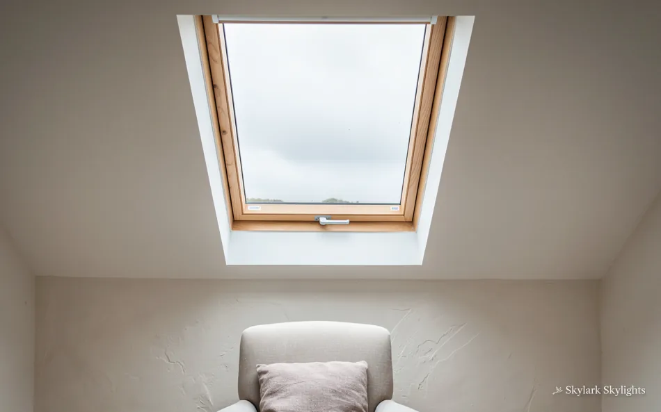 Armchair below a roof window in a plain attic room