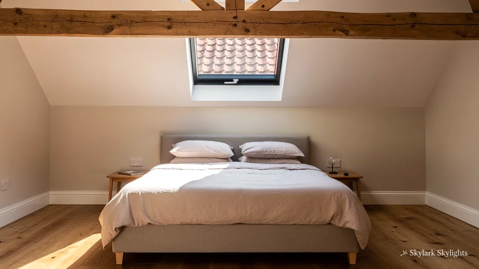 Beamed loft bedroom with a small rooflight in the slope above the bed