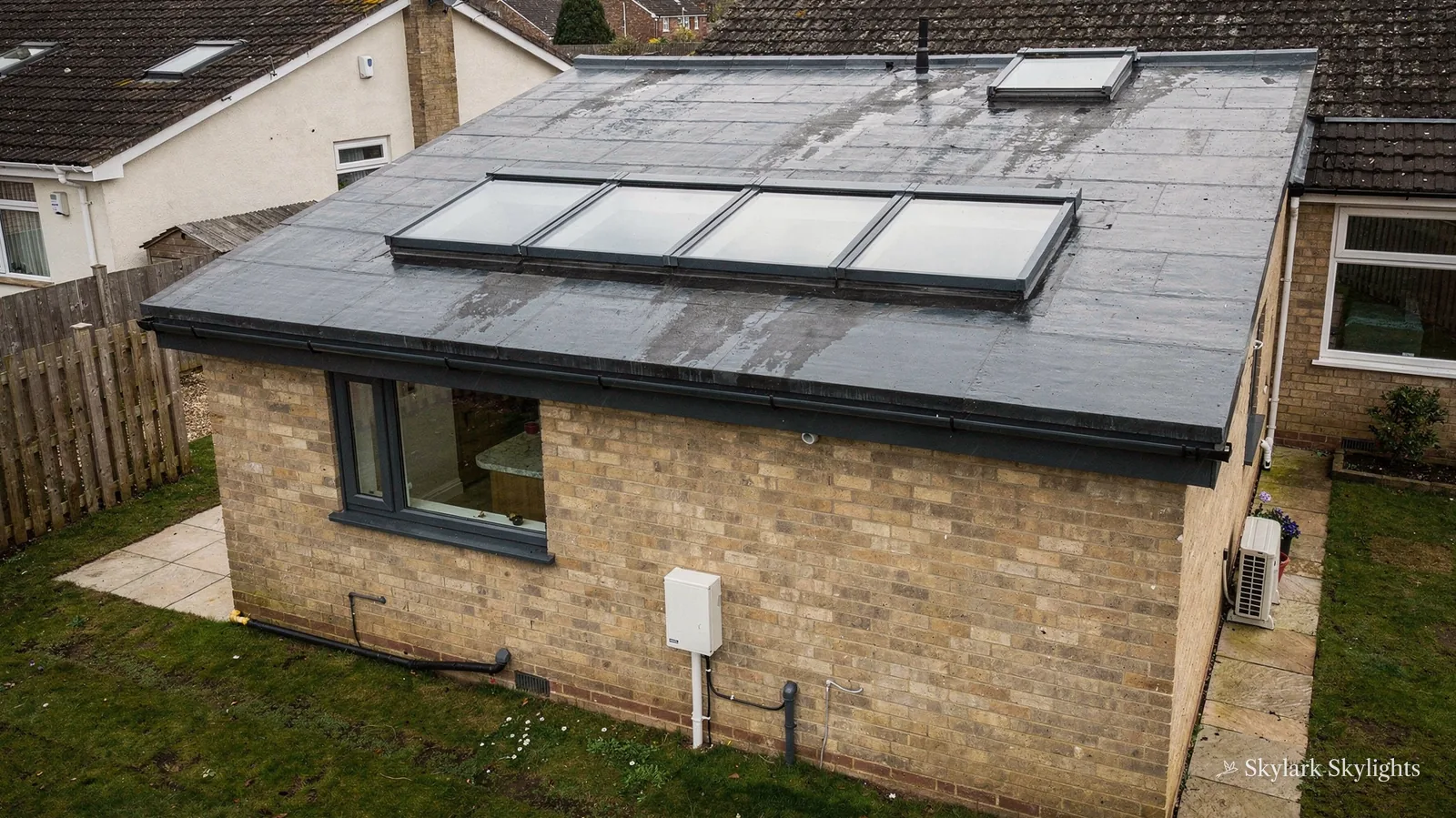 Single-storey brick extension with a long flat rooflight, seen from the garden