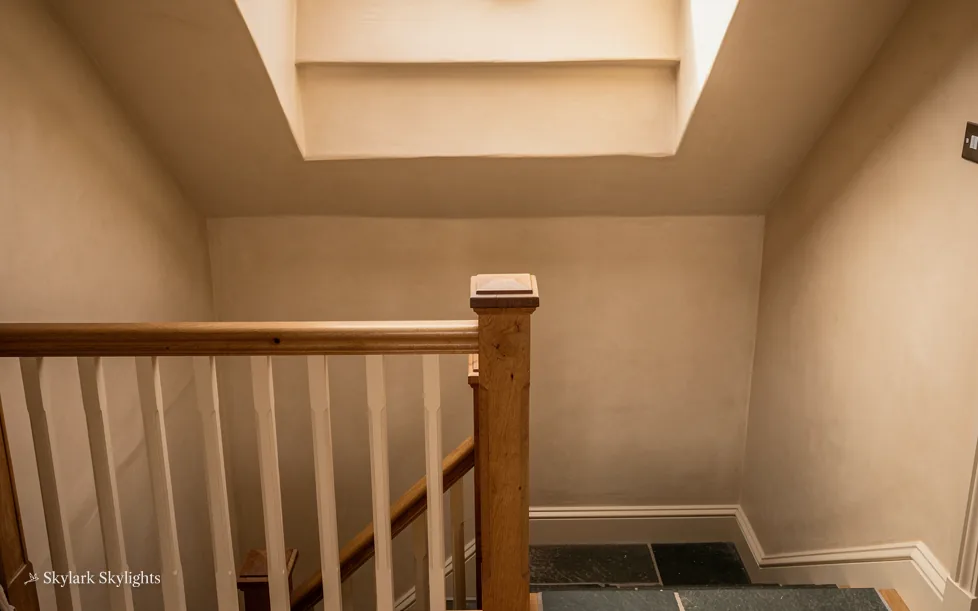 Top of a staircase in a loft with a rooflight above