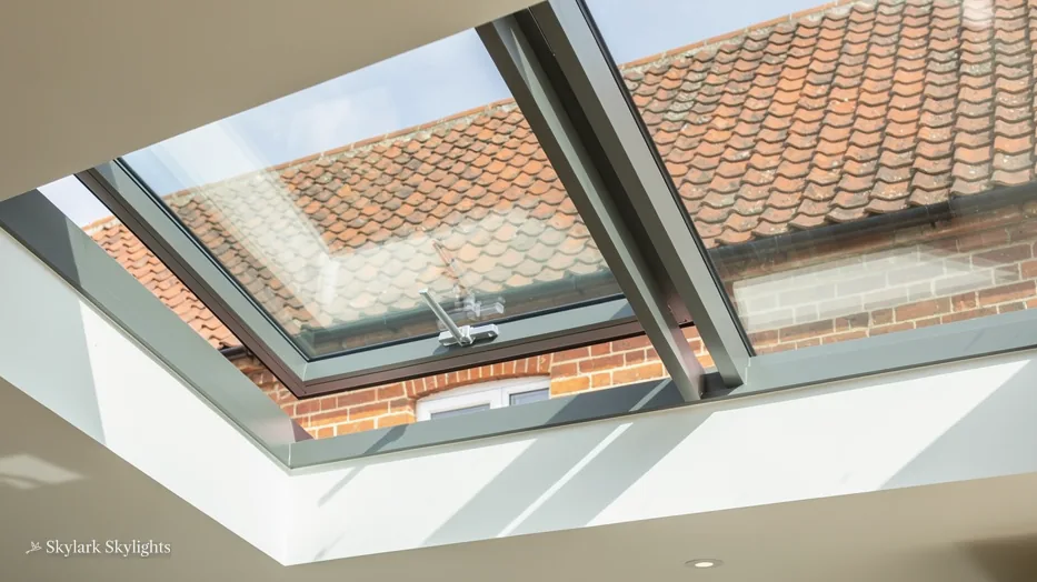 Close view of an opening rooflight propped open above a white room, tiles beyond