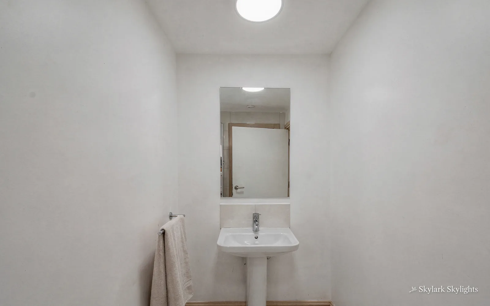 Basin and mirror in a small white cloakroom