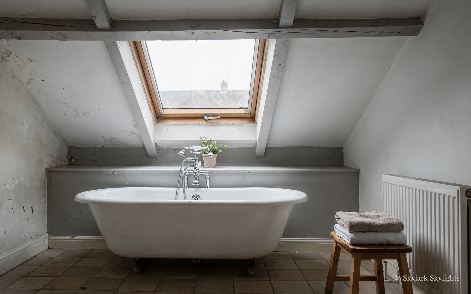 Loft bathroom with a roll-top bath under a roof window