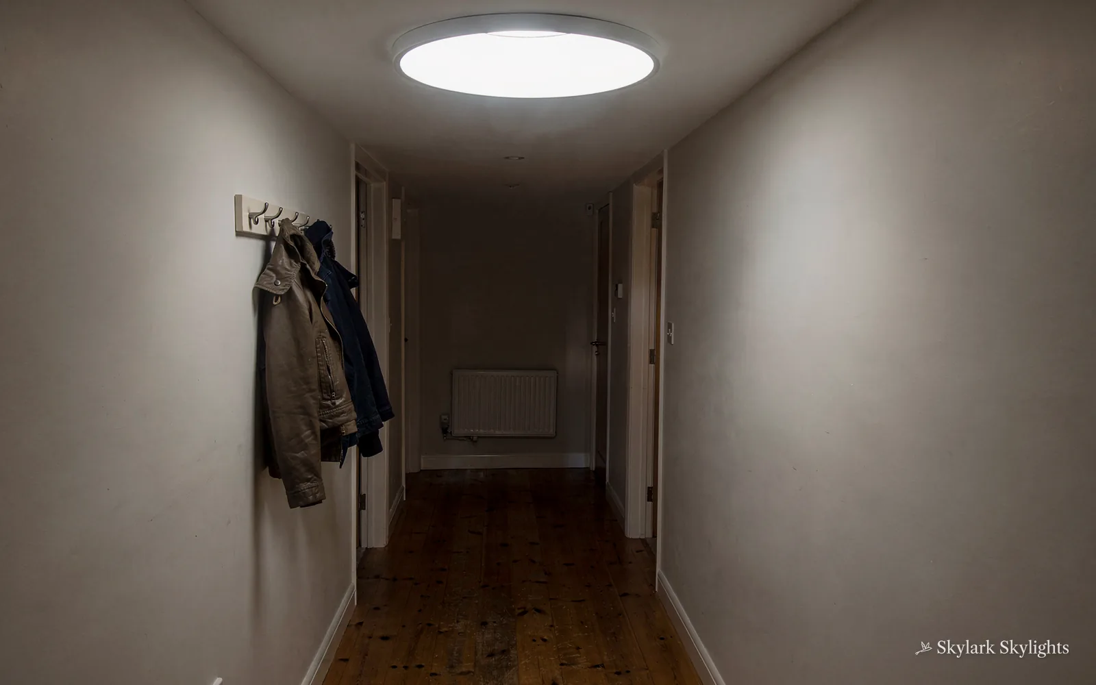 Hallway with coats on hooks and a sun tunnel in the ceiling
