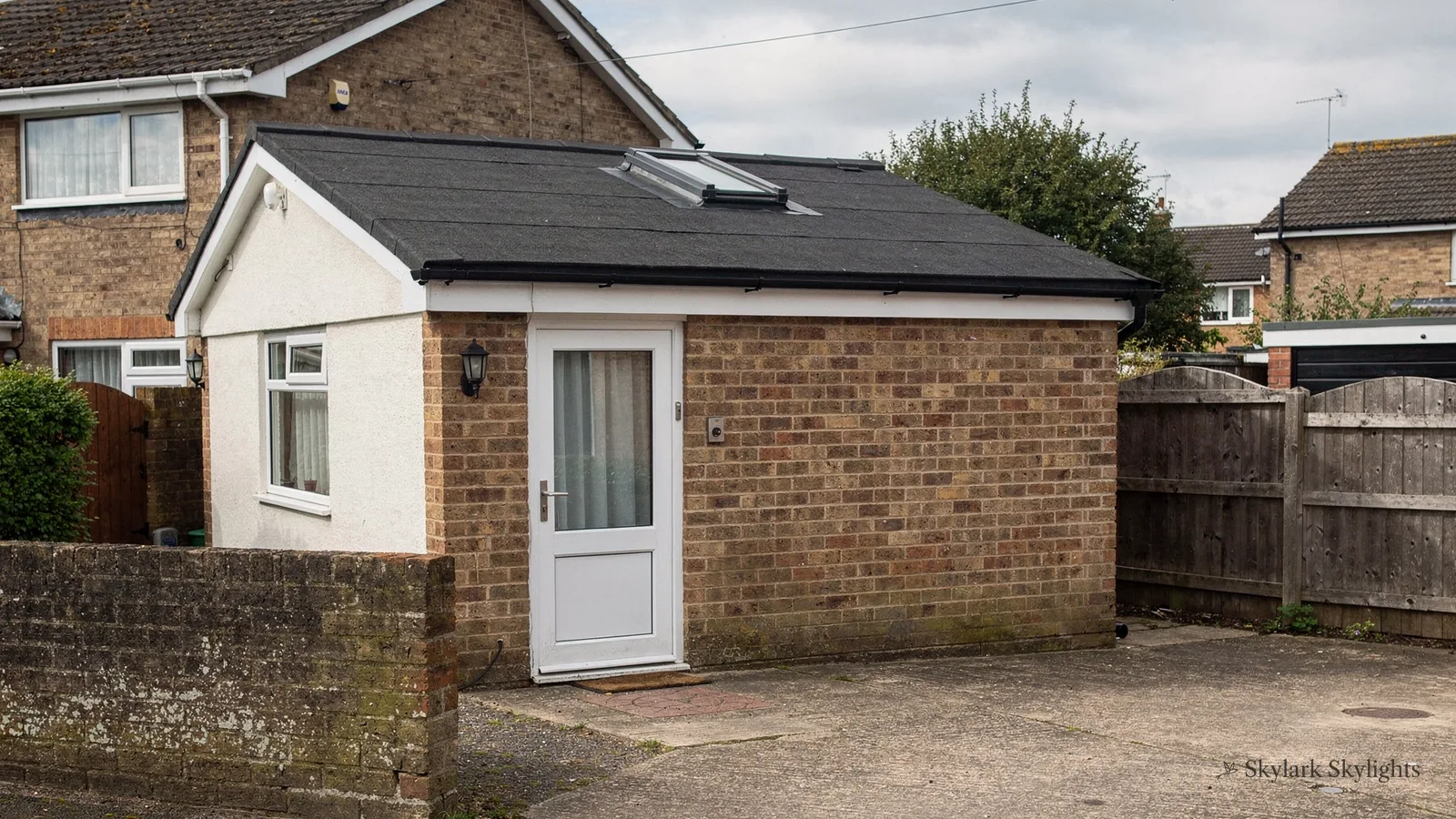 Brick garage conversion with a flat roof beside a semi