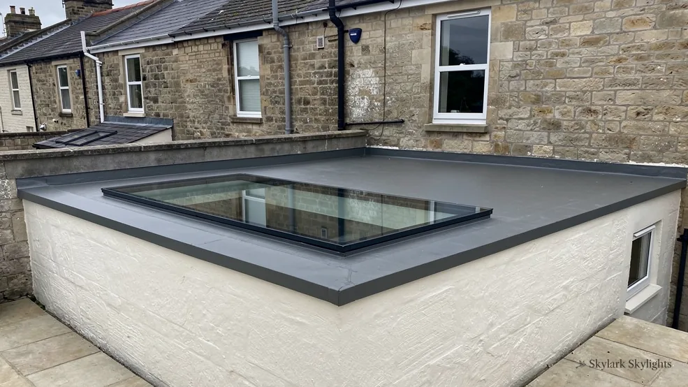 Flat rooflight on a rendered extension next to stone houses
