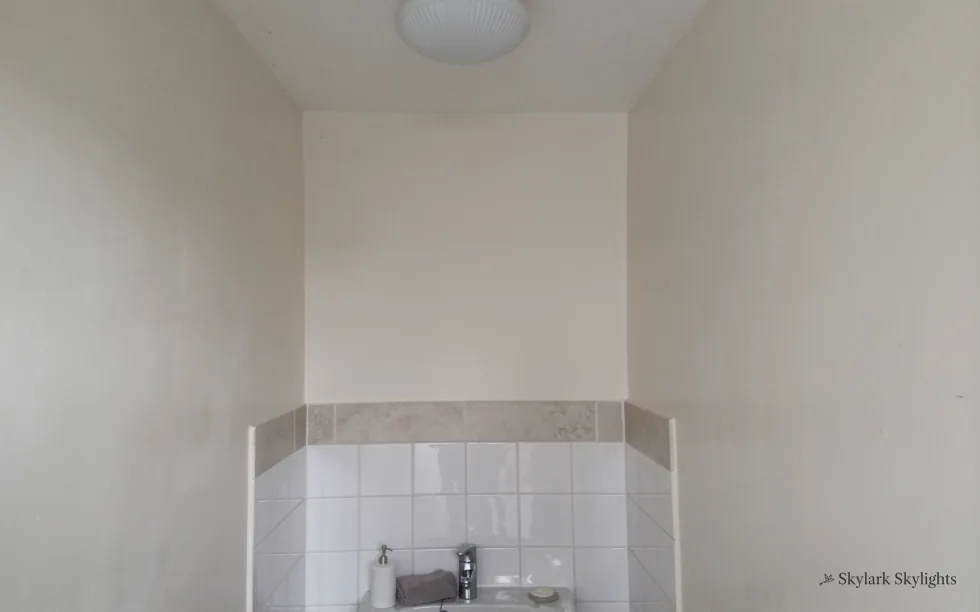 Corner of a small bathroom with a tiled splashback