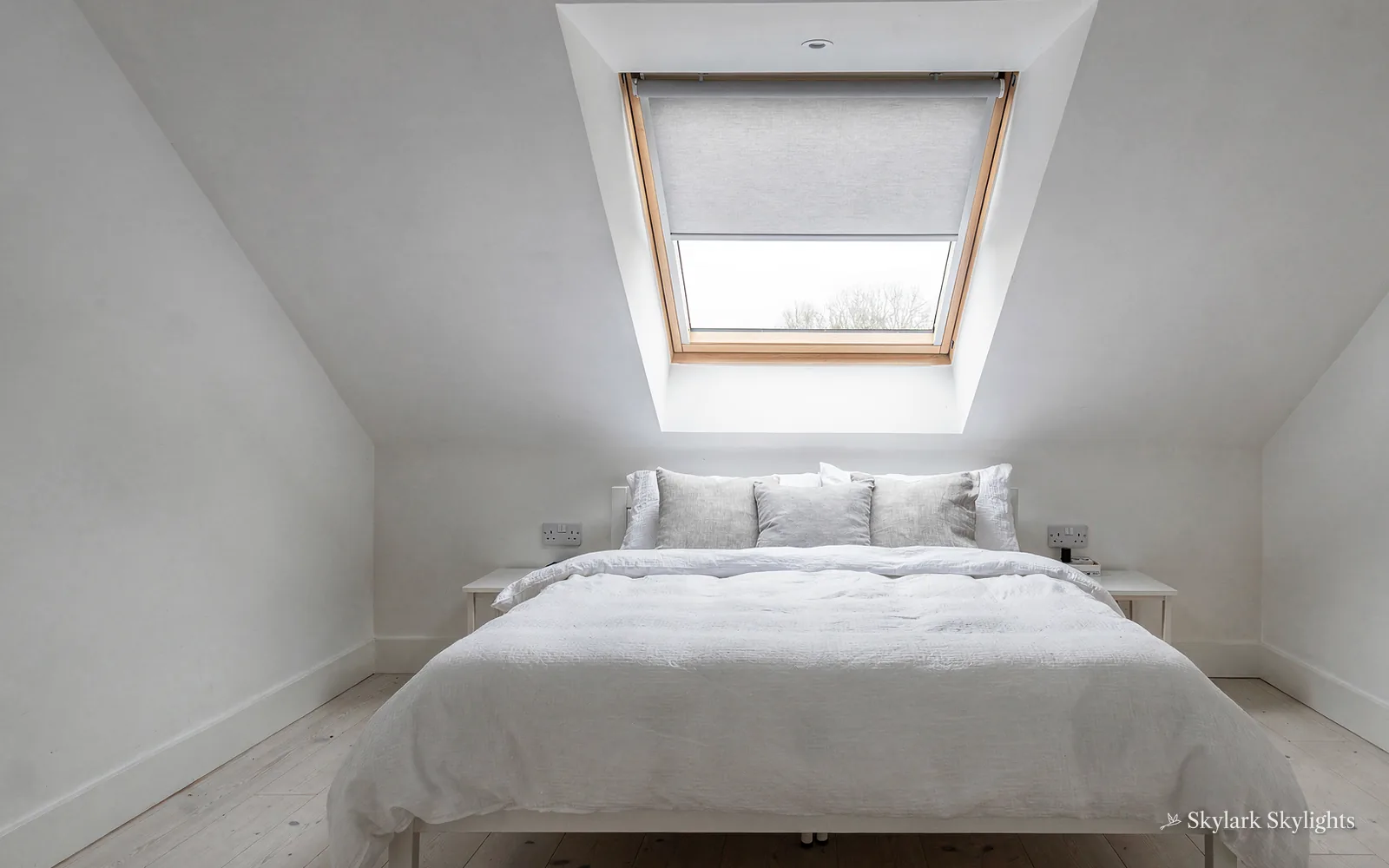 Bed under a roof window with a pleated blind