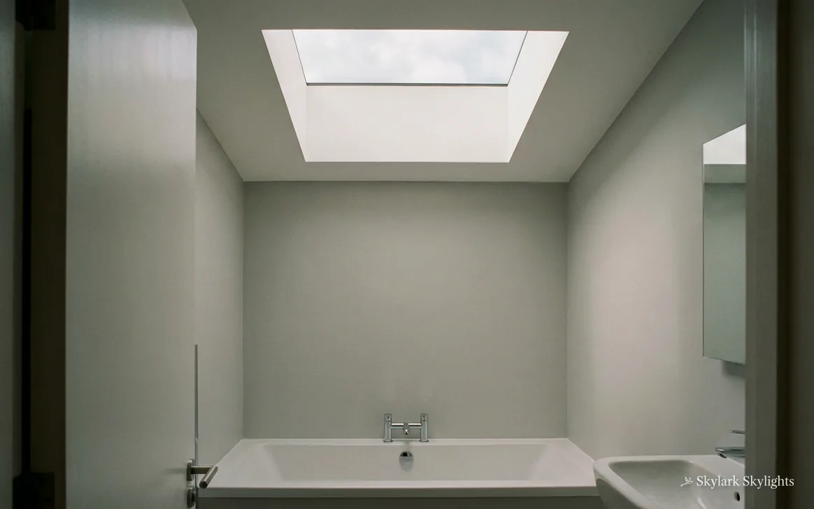 Narrow bathroom with a bath at the far end under a rooflight