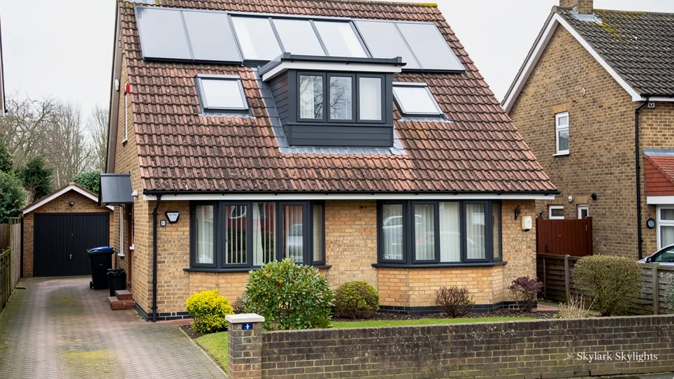 Brick house with a dormer and roof windows above a drive and garage