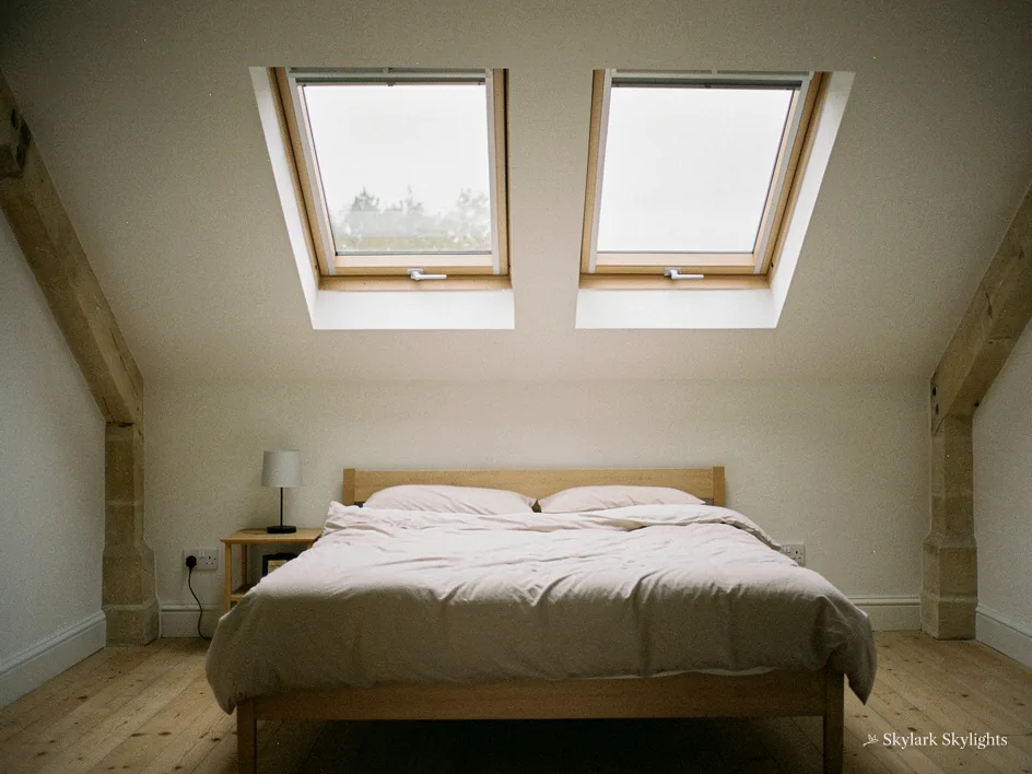 Attic bedroom with two roof windows above a double bed