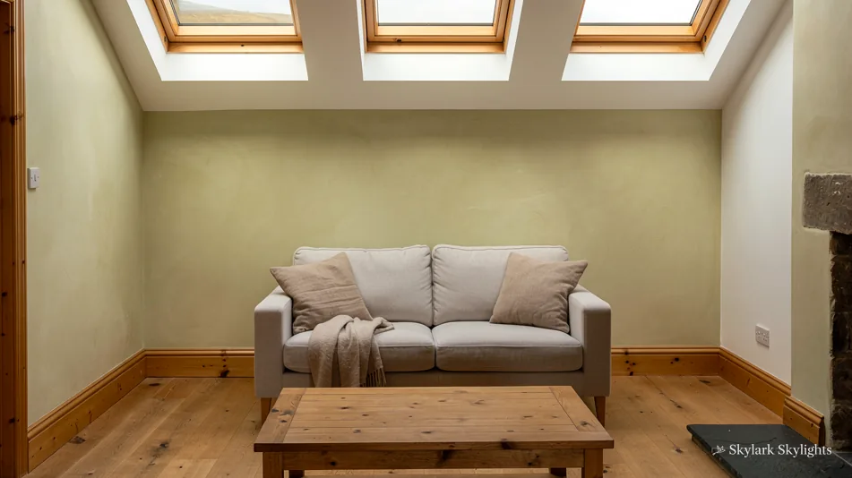 Loft lounge with a grey sofa below a row of three roof windows