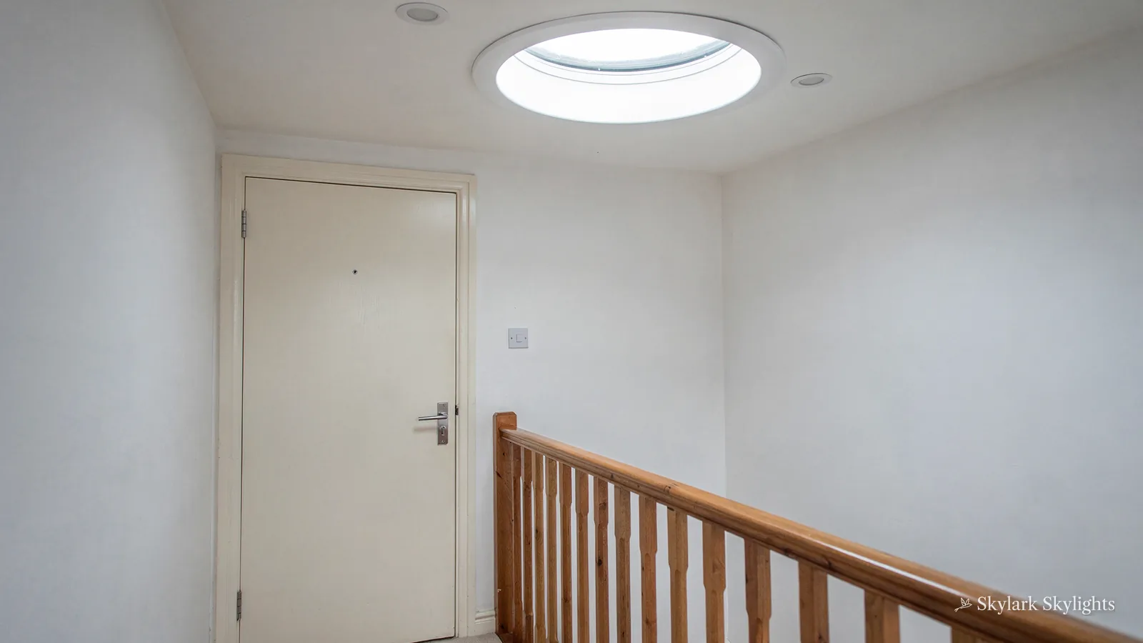 Upstairs landing with a timber banister and a round sun tunnel in the ceiling