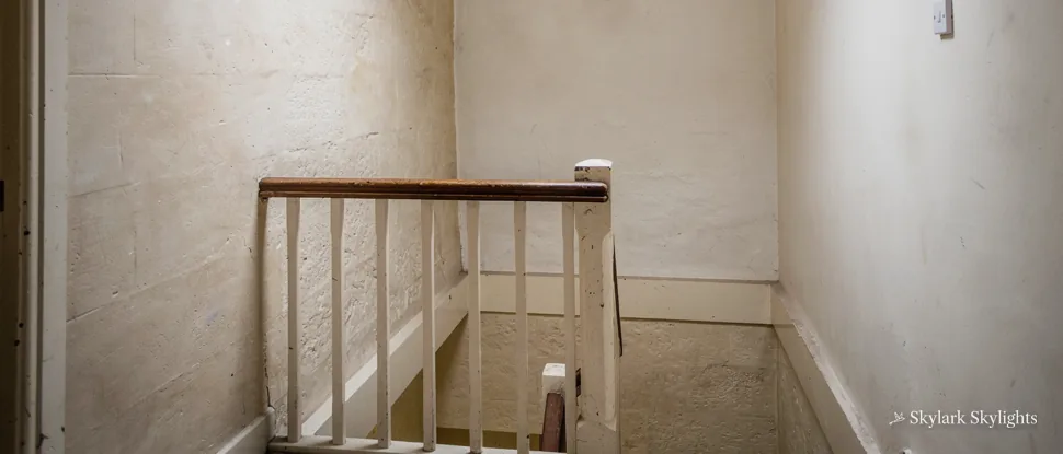 Small landing with a white banister in a windowless stairwell