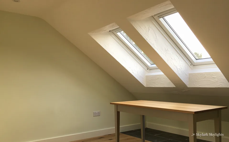 Desk under two roof windows in a sloping loft room