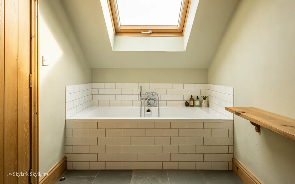Bathroom with a tiled bath panel under a roof window