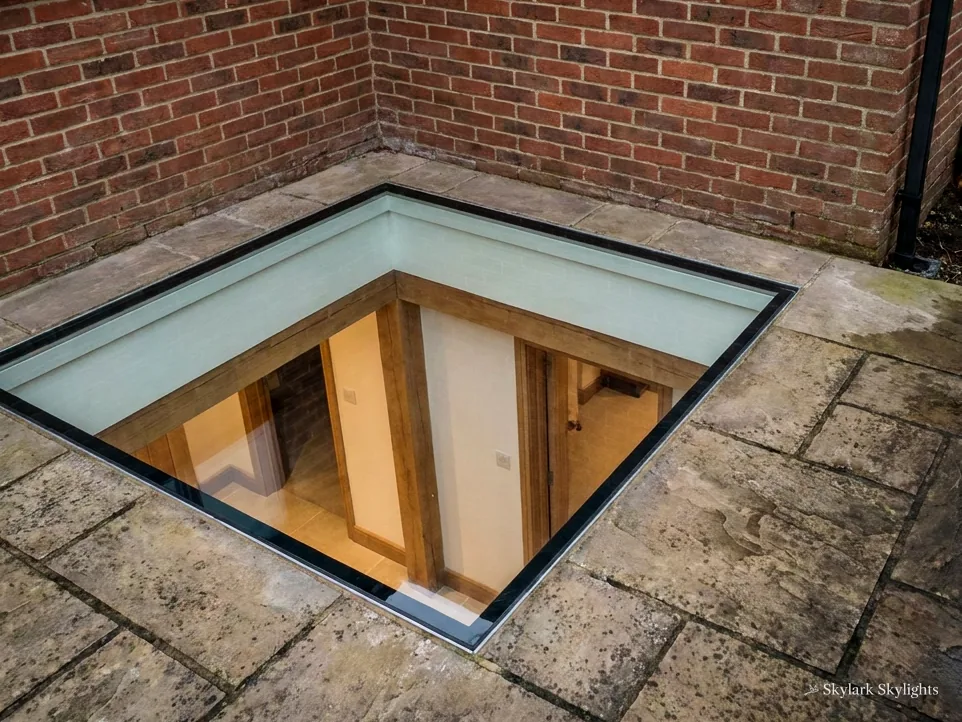 Walk-on rooflight set into paving, with a staircase visible beneath