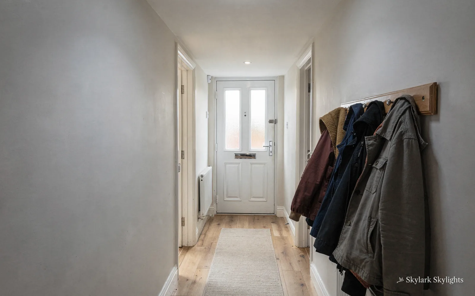 Hallway with coats on pegs by the front door