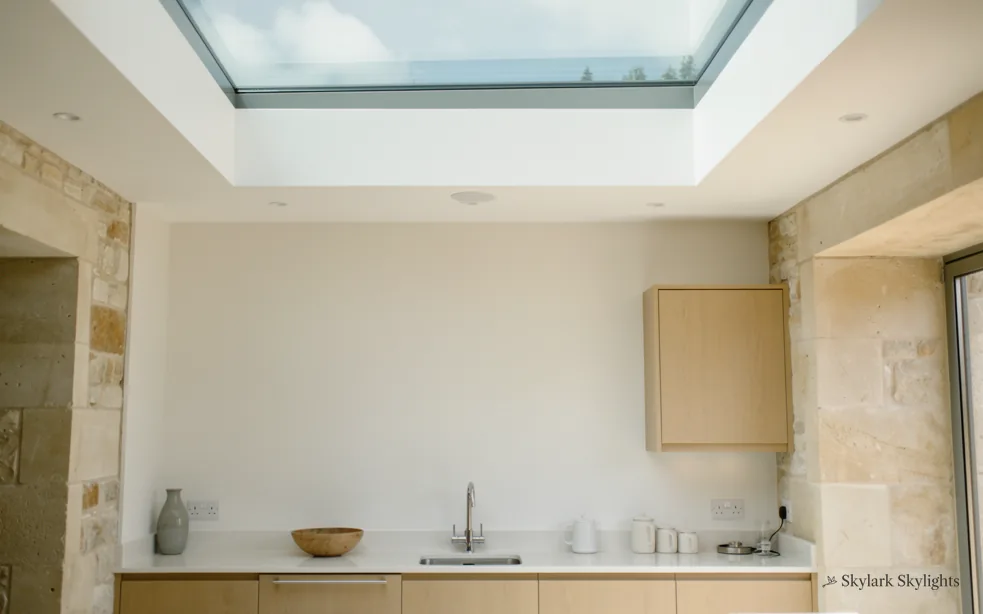 Narrow galley kitchen with a stone wall and a rooflight above